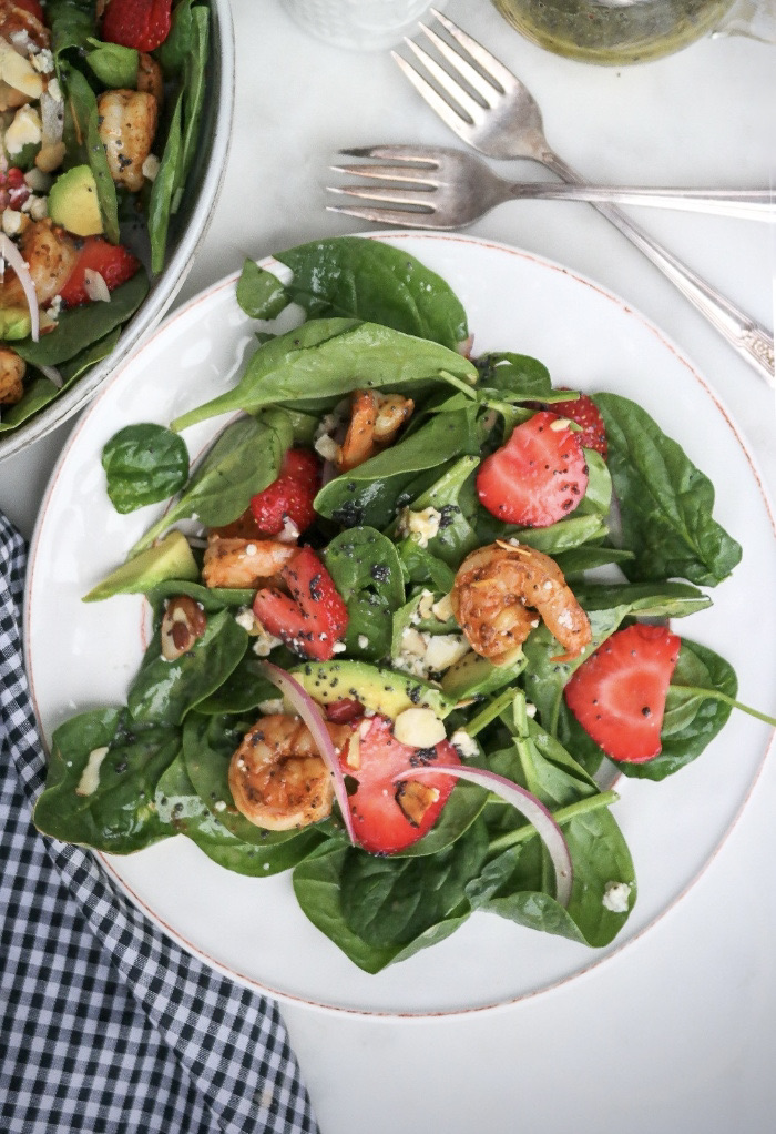 Top view of spinach strawberry salad topped with shrimp.
