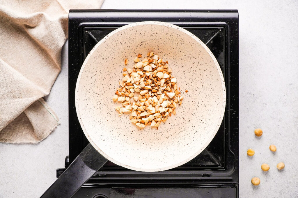 Roasting chipped macadamia nuts in a saucepan.