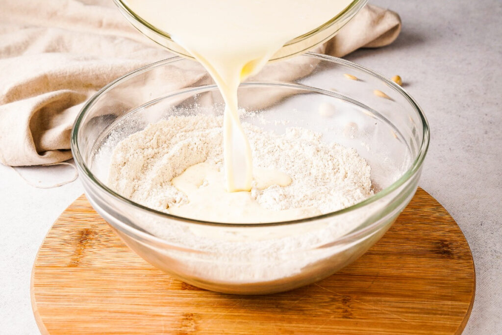 Mixing wet and dry ingredients together to make a pancake batter.