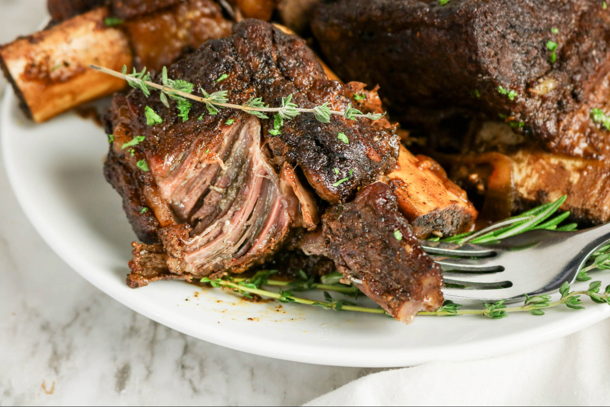 A fork tenderly pulling beef short ribs from the bone.