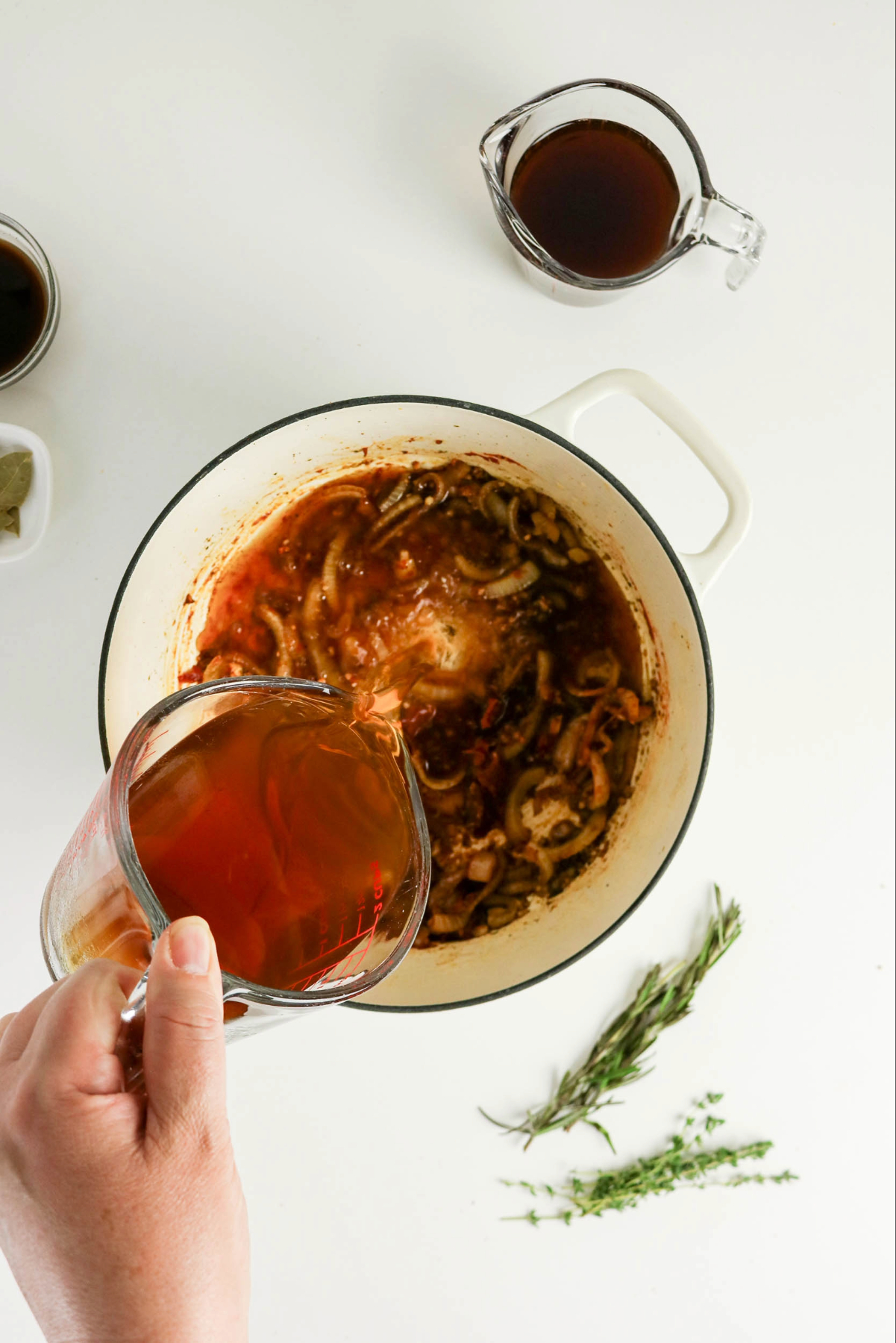 Pouring beef broth over cooked onion broth mixture.