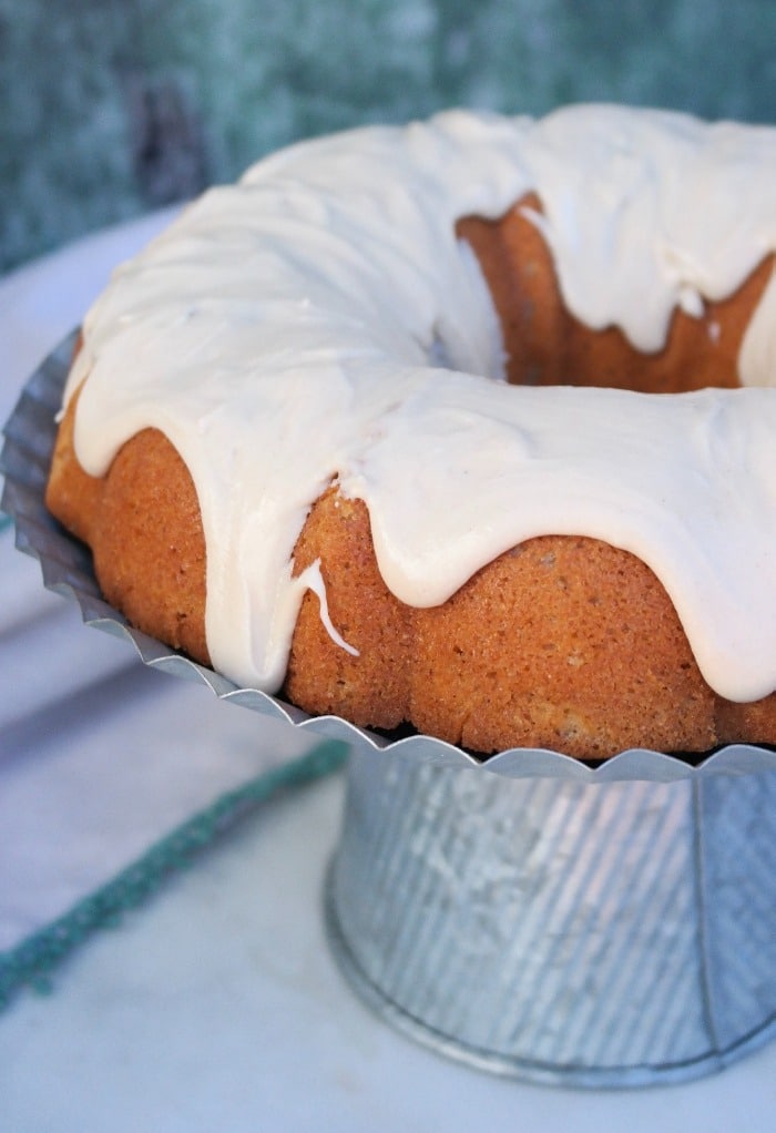 Spice bundt cake topped with icing on an aluminum cake plate. 