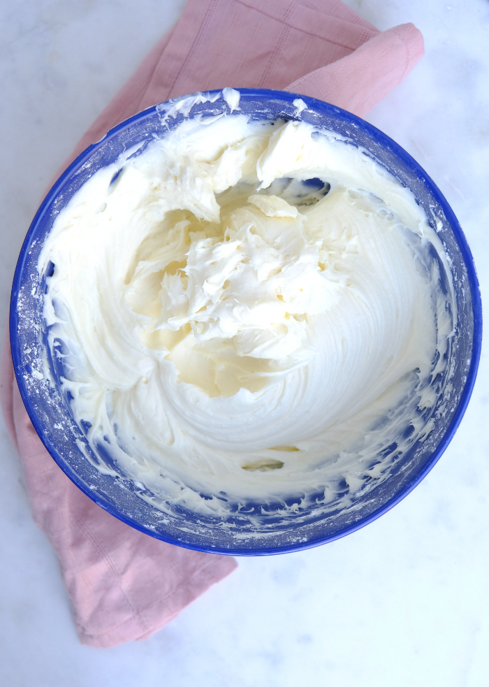 Cream cheese frosting in a blue rimmed mixing bowl.