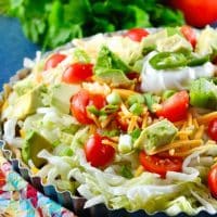 taco pie topped with lettuce and tomatoes