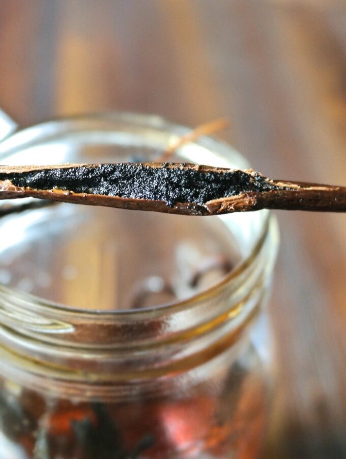 Homemade vanilla extract in a mason jar with a fresh vanilla bean