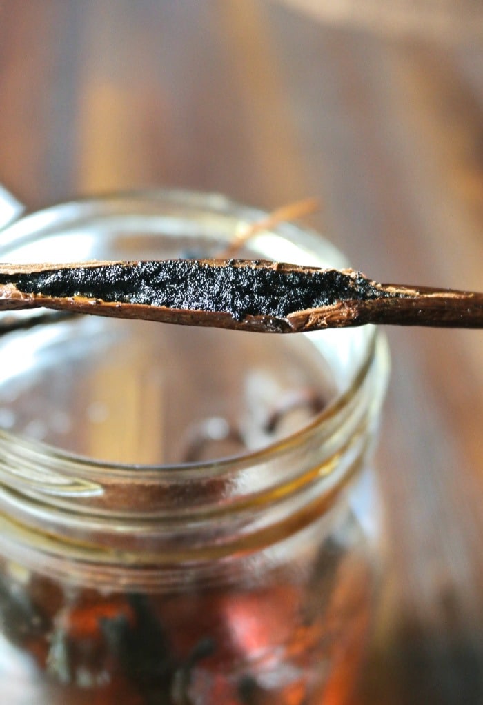 Homemade vanilla extract in a mason jar with a fresh vanilla bean