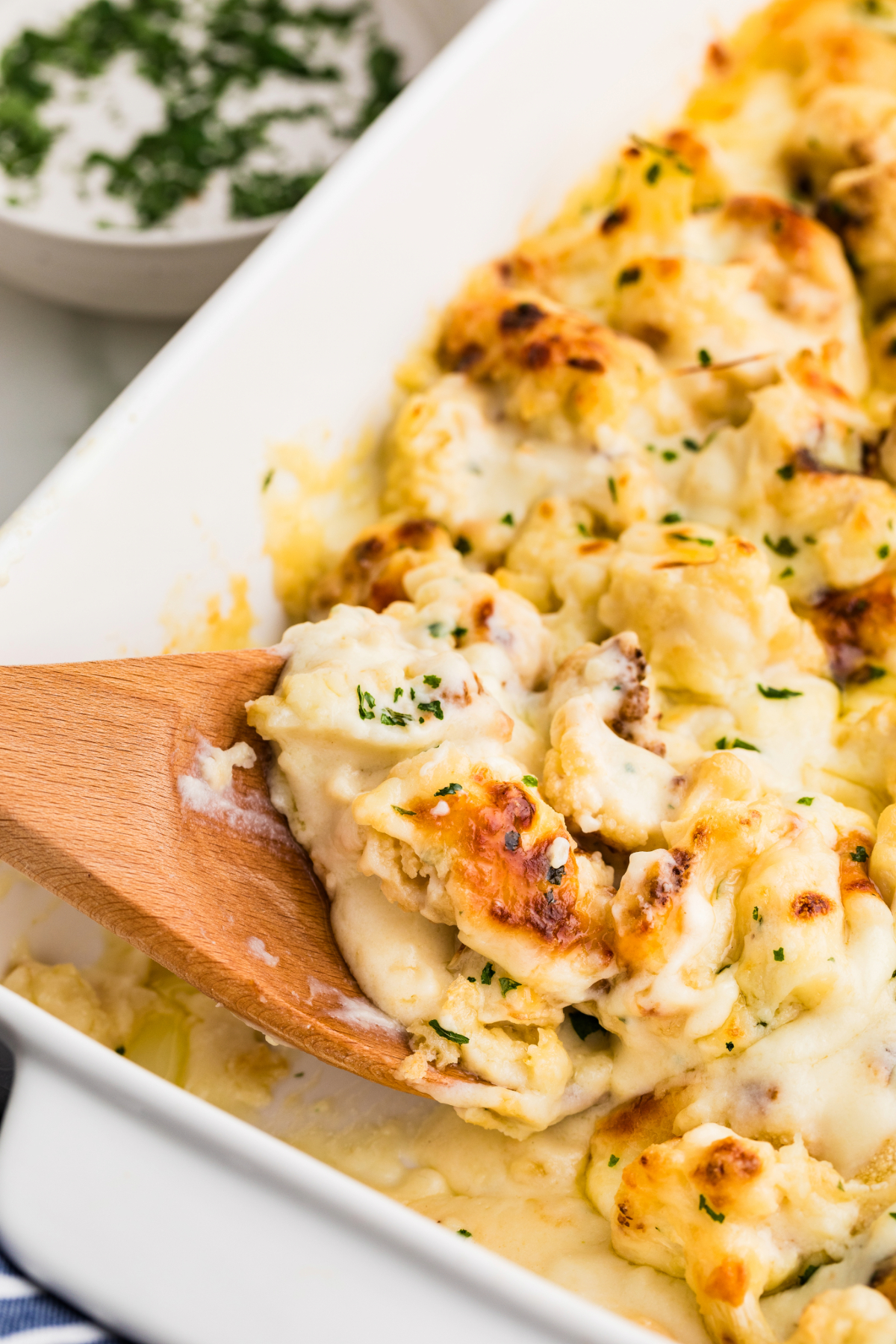 Baked cauliflower casserole with a cheese sauce in a white serving dish. 