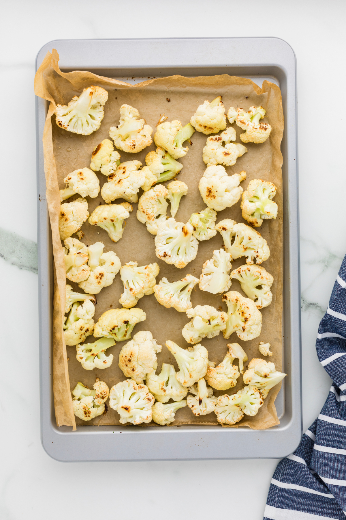 Roasted cauliflower florets on a baking sheet lined with parchment paper.
