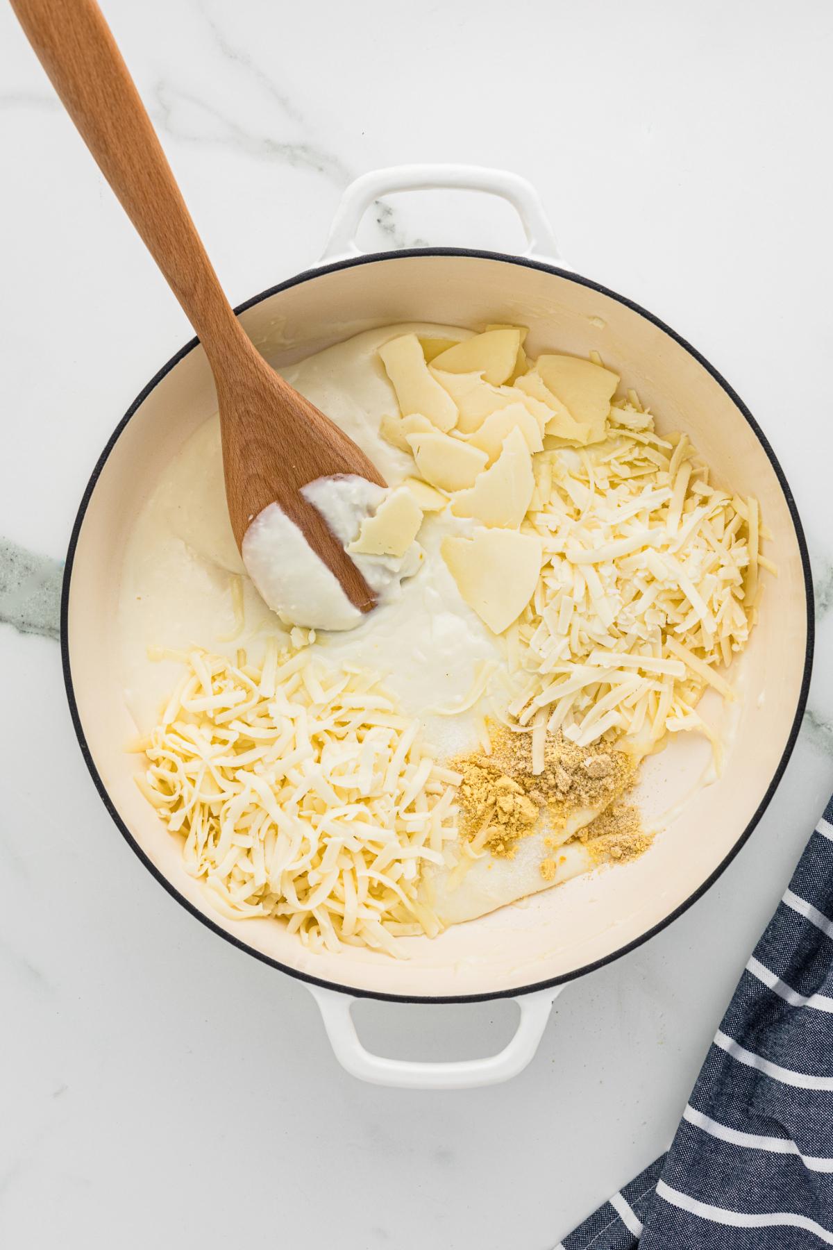 Milk and cheese in a large Dutch pan cooking a cheese sauce.