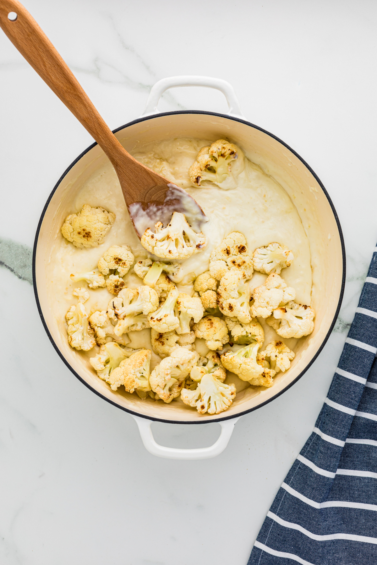 Adding cauliflower to the cheese mixture.