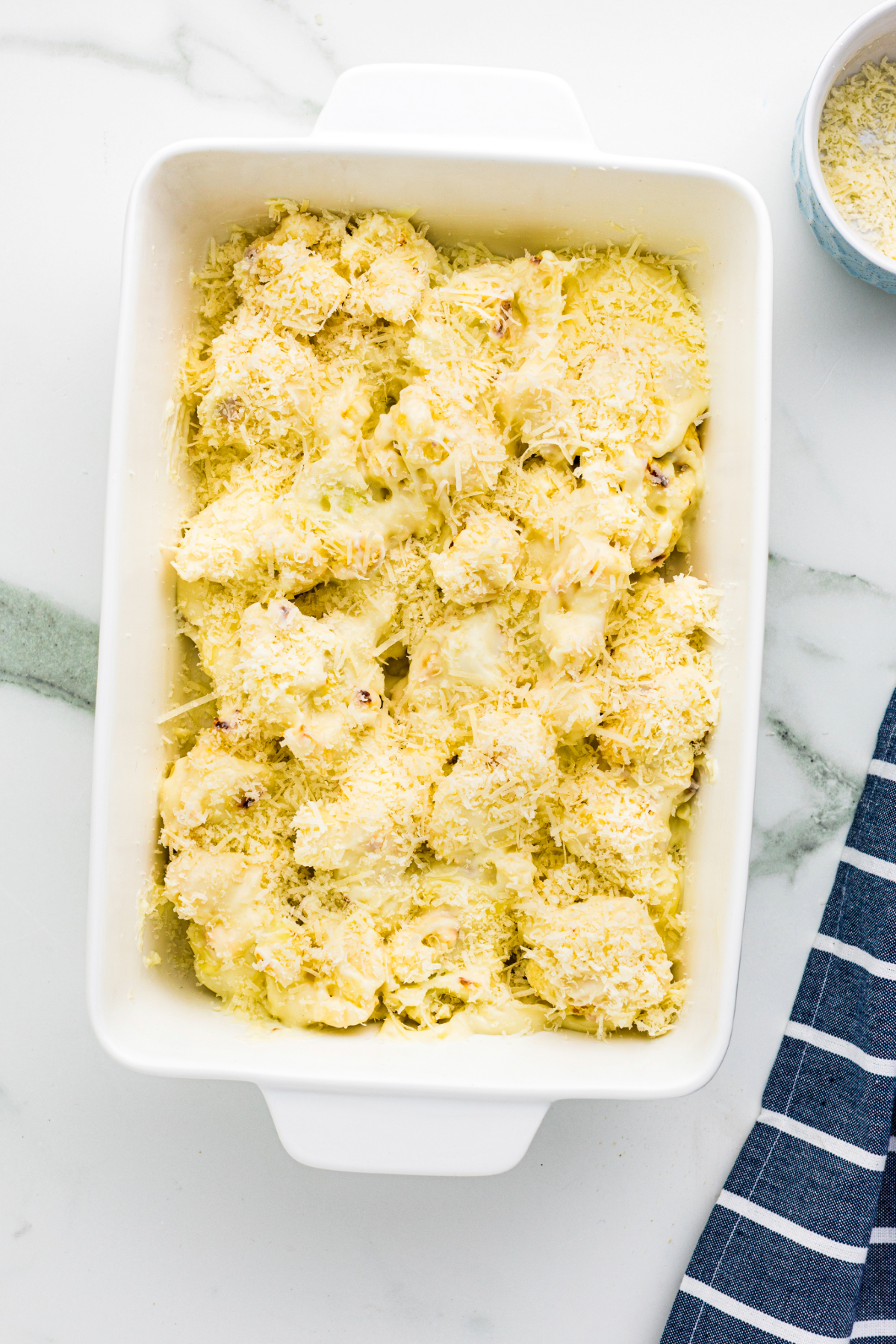 Cheesy cauliflower mix in a white baking dish before placing in the oven. 