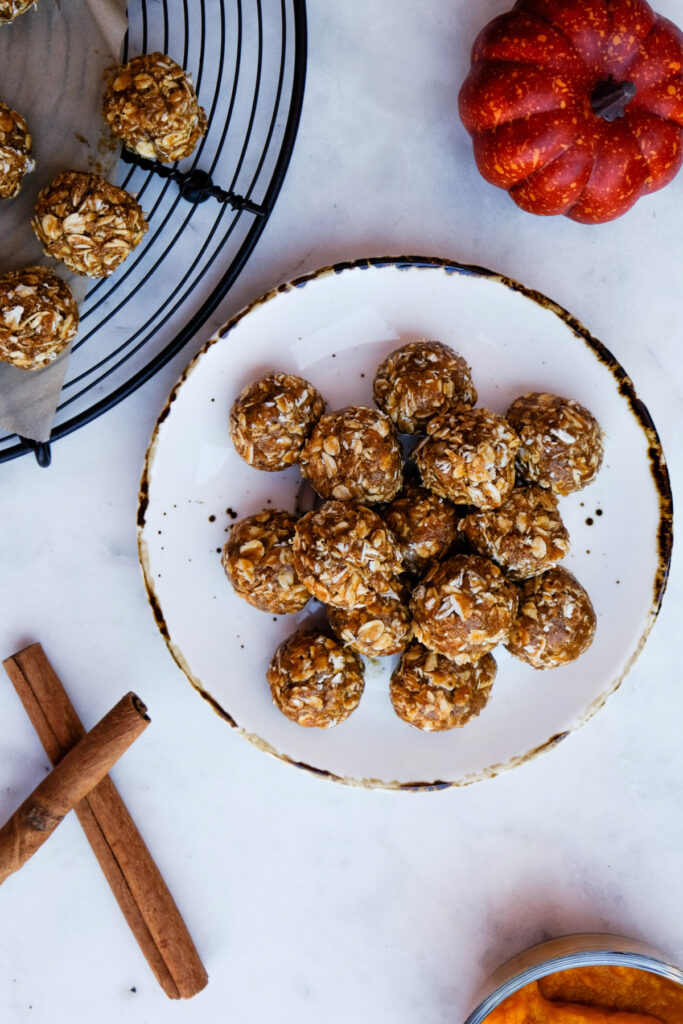 Overhead view of no bake pumpkin protein bites on a white plate with a tan rim.