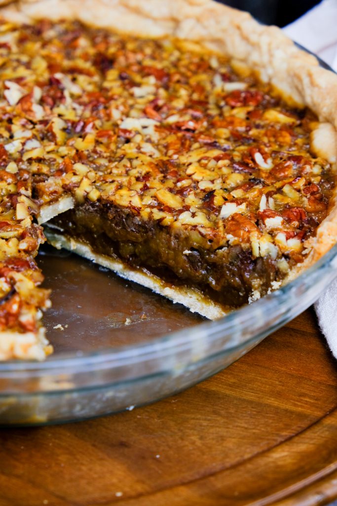 A glass pie pan with a slice of pecan pie taken out. 