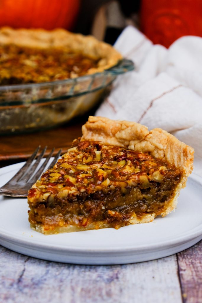 A slice of old fashioned pecan pie on a white plate. 