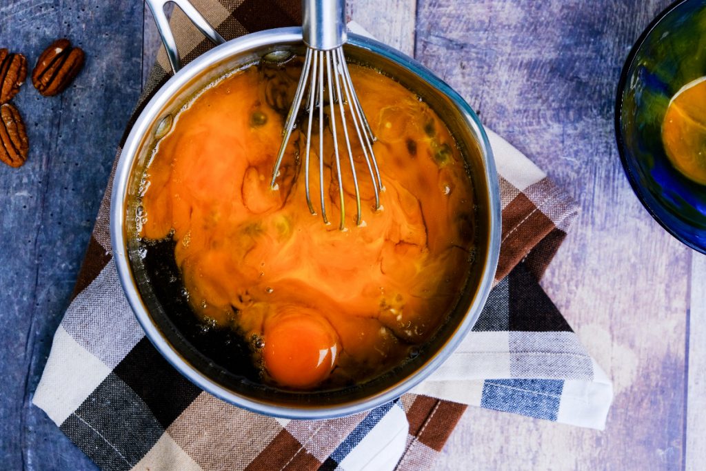 Egg yolks whisked into a maple syrup filling for pie. 