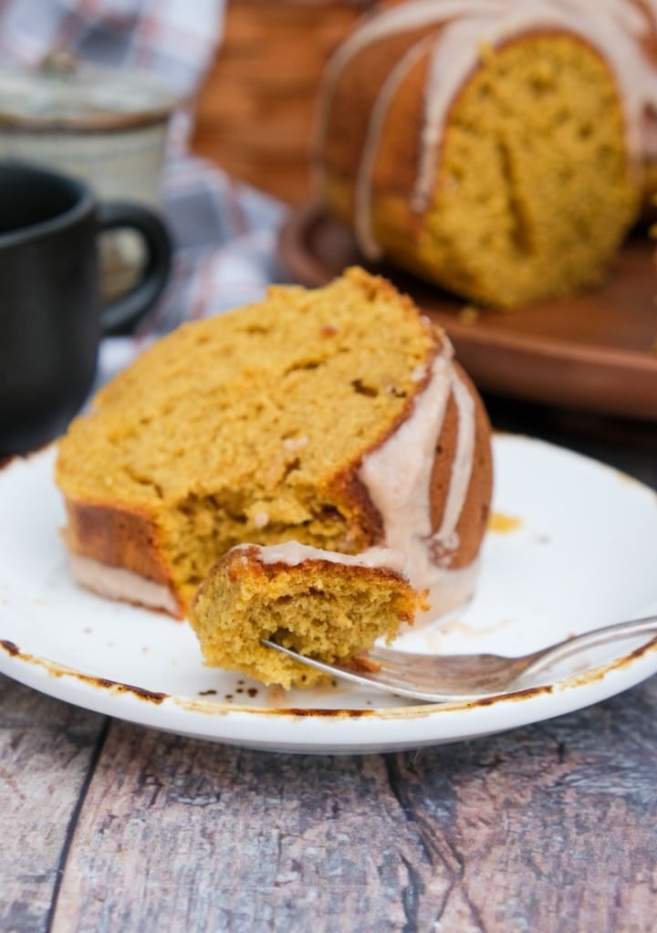 Slice of cake of a white plate with a fork taking a piece ready to eat. 