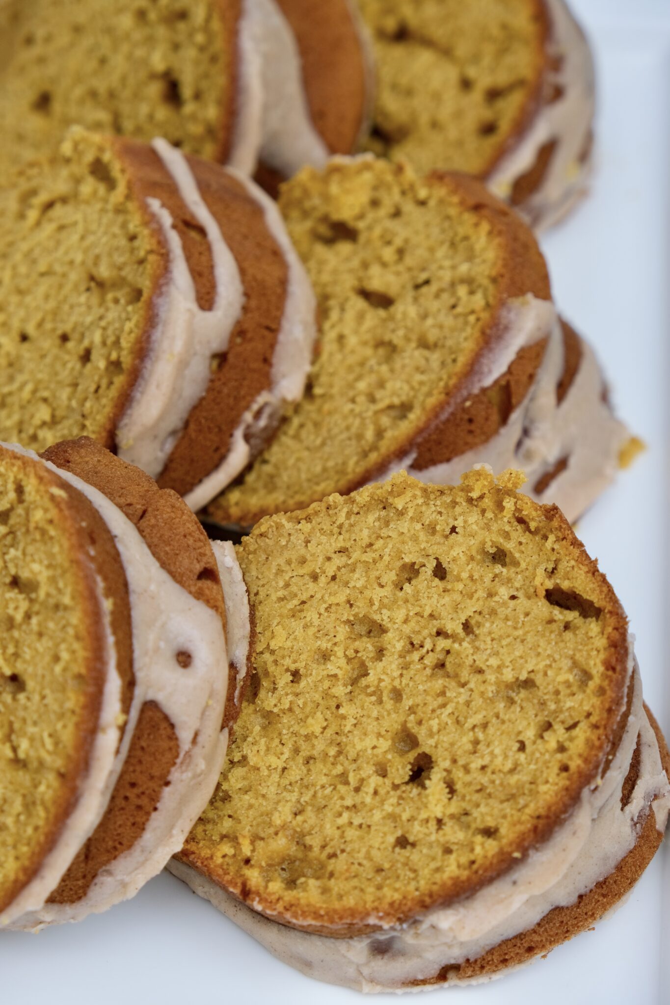 Overhead view of sliced pumpkin spice bundt cake on a white serving platter.