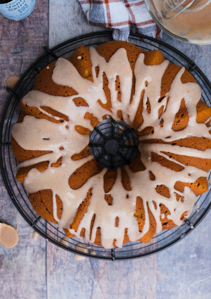 Overhead view of pumpkin spice bundt cake on a cooling rack with drizzle of icing over the cake.