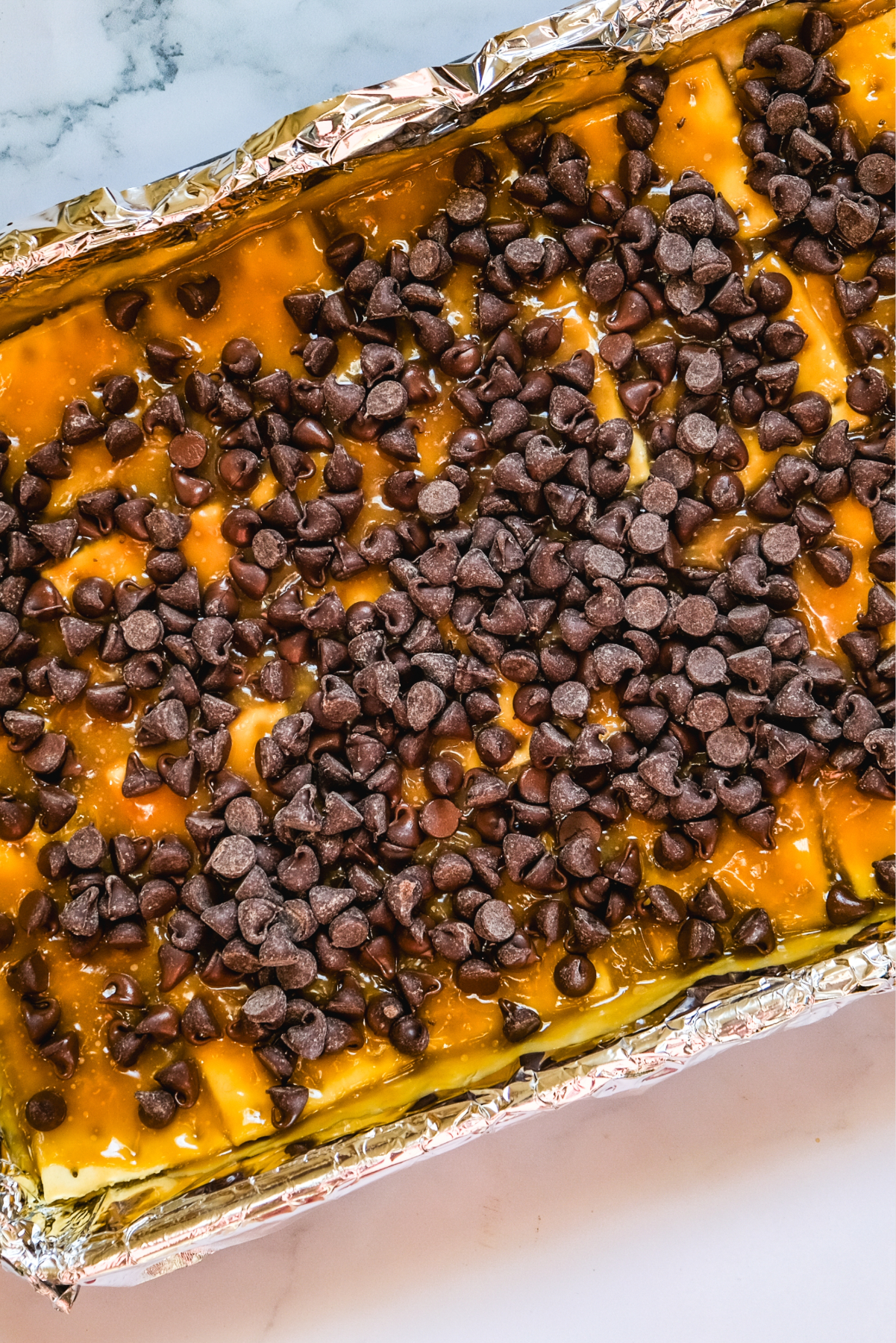 Chocolate chips sprinkled over caramel lined with saltine crackers.