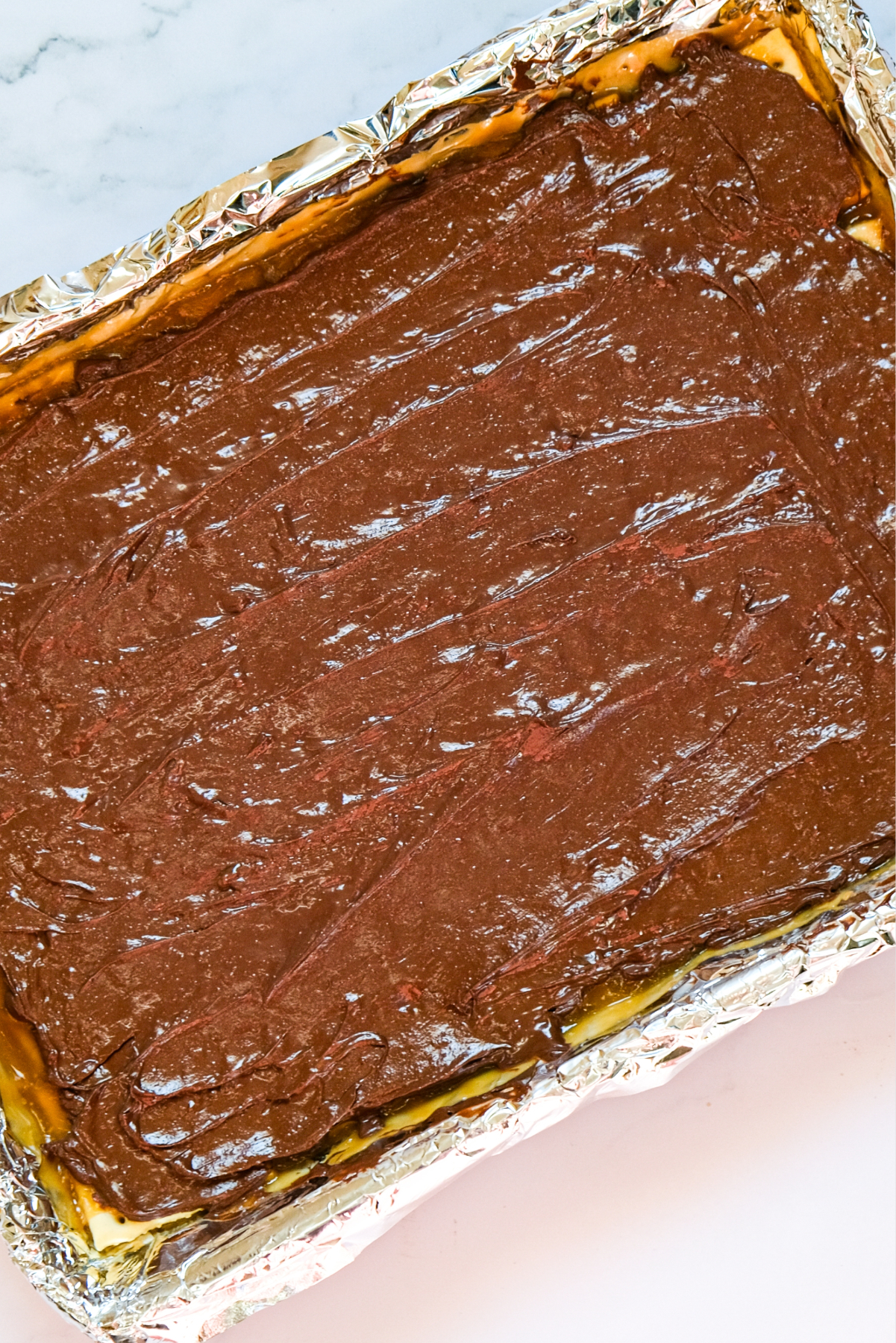 Melted chocolate chips spread over saltine caramel mix.