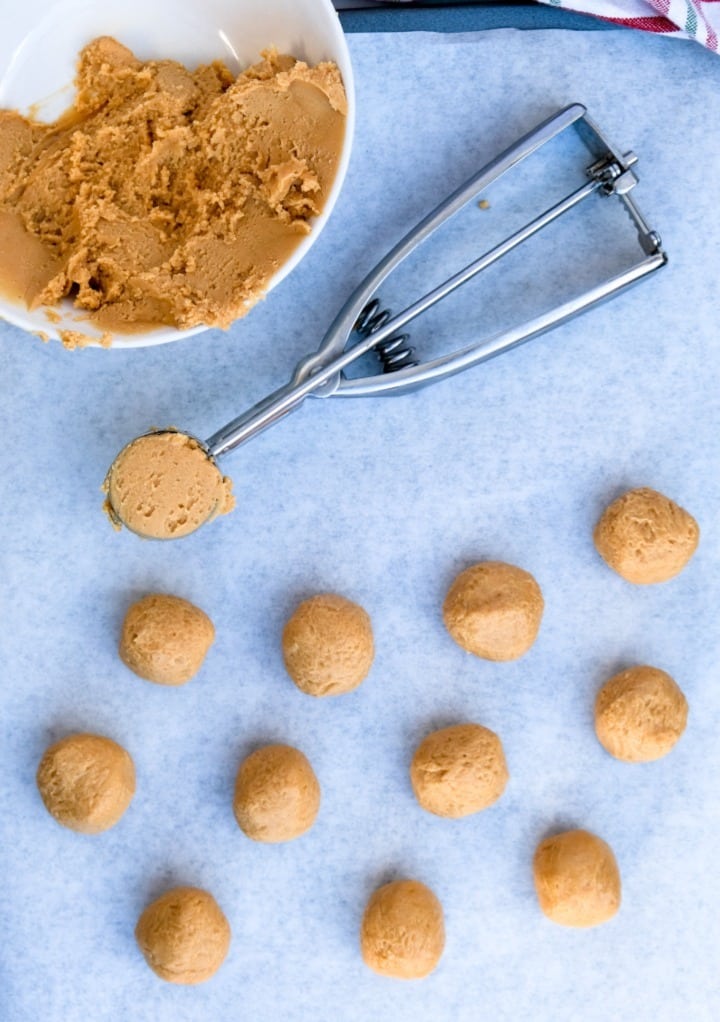 Cookie dough rolled in small balls placed on a baking sheet lined with parchment paper. 