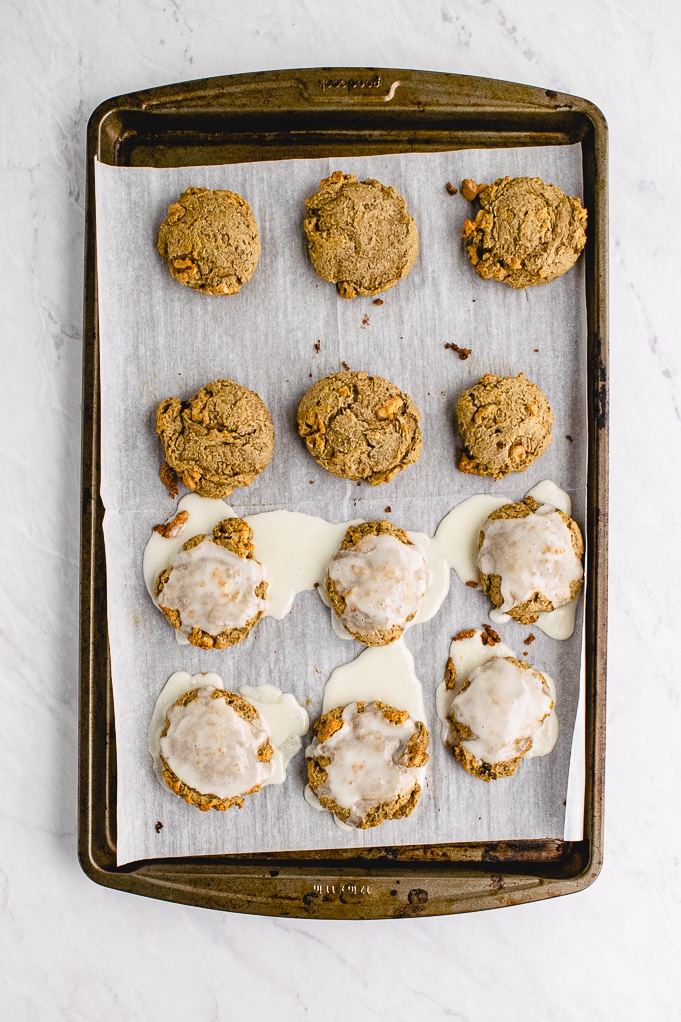 Baked cookies on a baking sheet with some topped with a glaze. 