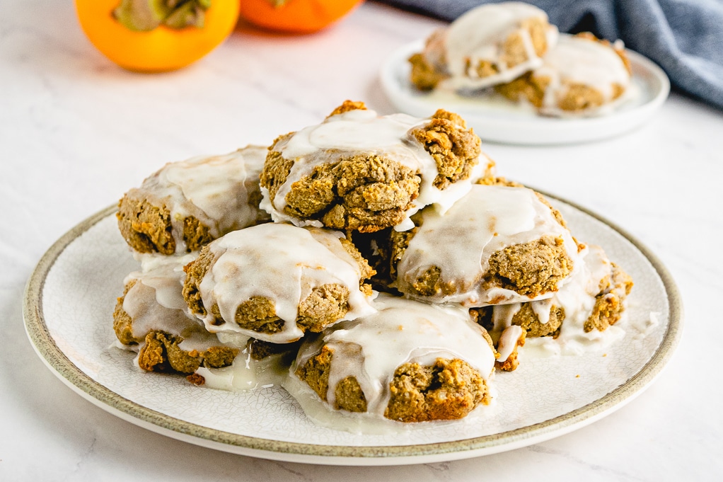 Plateful of cookies with fresh persimmon in the back. 