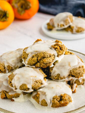Persimmon cookies on a white plate topped with sugar glaze.