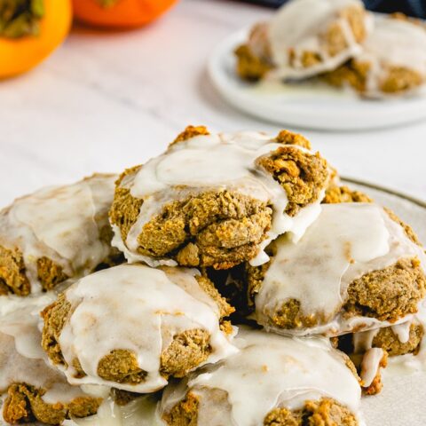 Persimmon cookies on a white plate topped with sugar glaze.