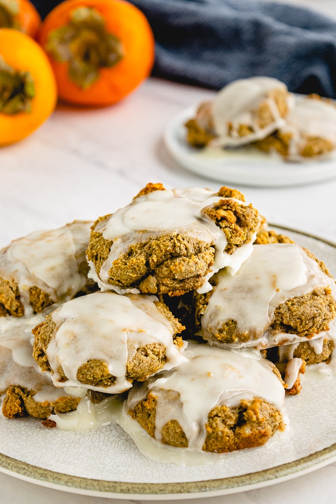 Persimmon cookies on a white plate topped with sugar glaze.