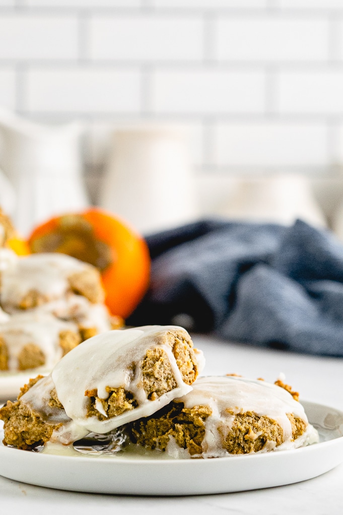 A white serving plate with persimmon cookies with a fresh persimmon in the background. 