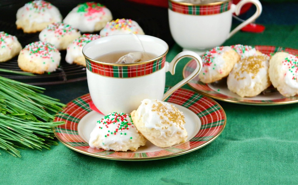 Holiday cookies on a plate with a cup of tea on the side