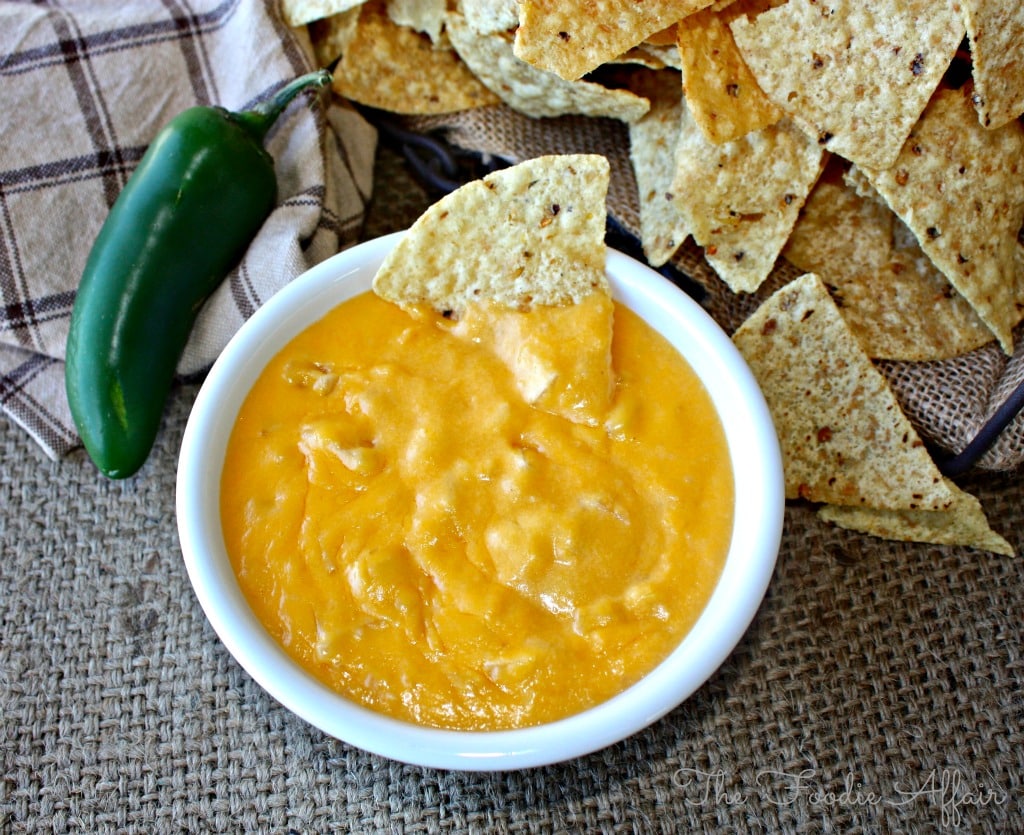 homemade nacho cheese sauce in a white bowl with tortilla chips