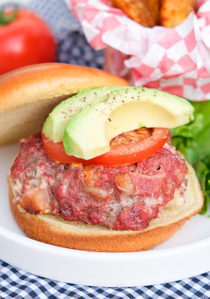 Blue cheese burger topped with tomato and avocado slices. 