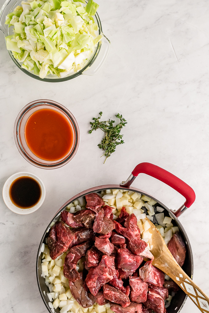 Meat filling for savory hand pies cooking in a skillet.