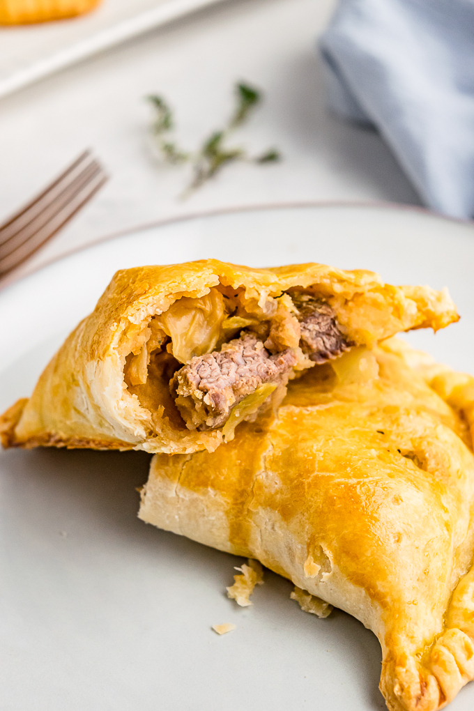 A plate with meat pie with a bite taken. 