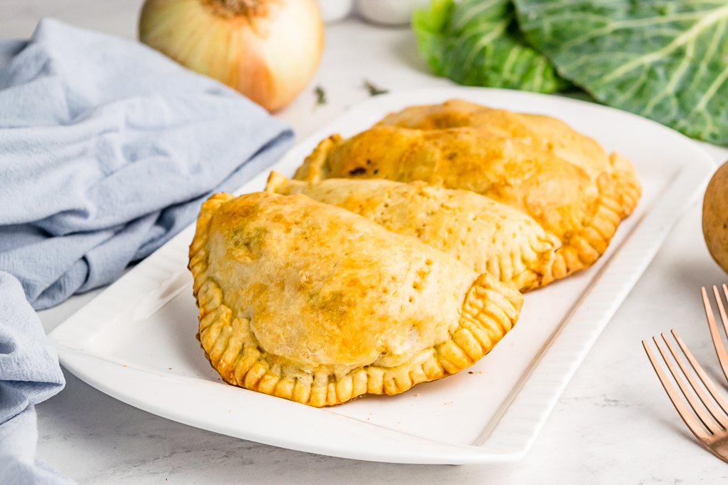 Cooked meat pies on a white serving dish.