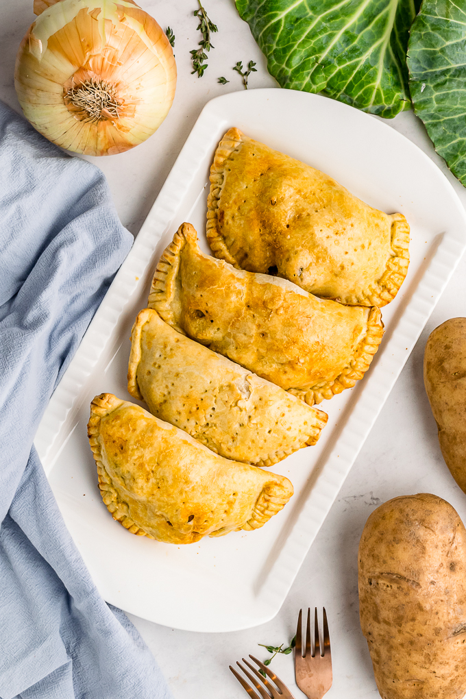 Baked meat pies on a white serving platter.