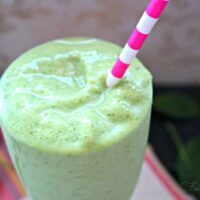 Spinach Avocado Smoothie in a clear glass with a pink and white straw