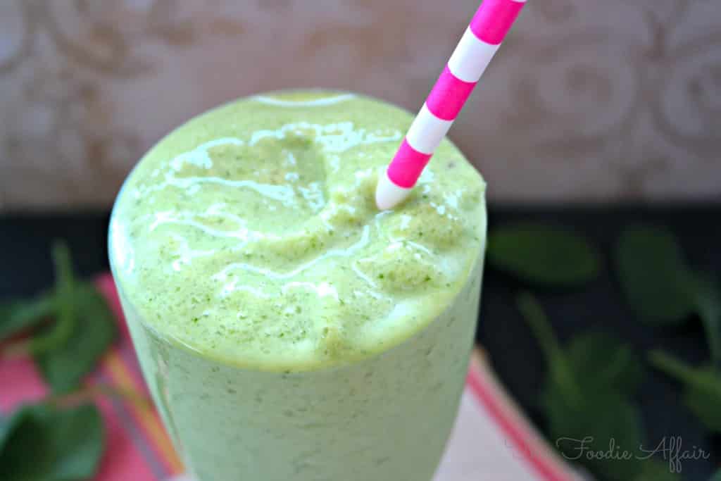 Spinach Avocado Smoothie in a clear glass with a pink and white straw