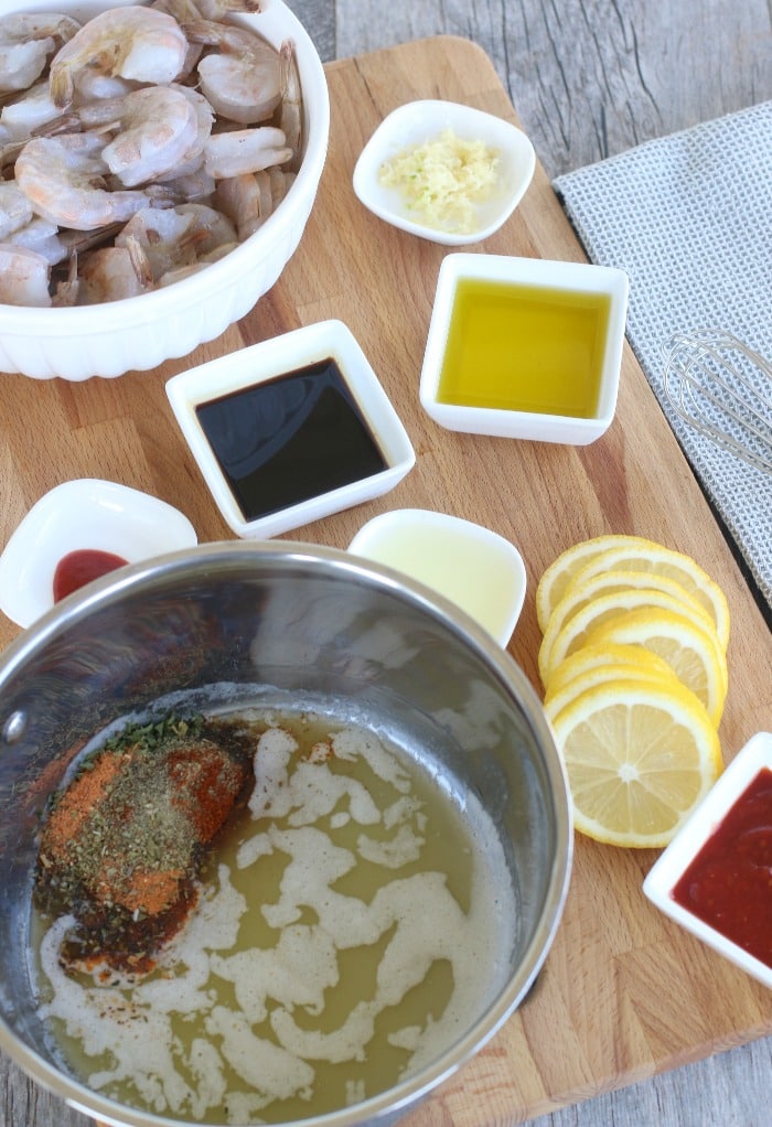 Adding spices to melted butter in a bowl to make the marinade for BBQ Shrimp.