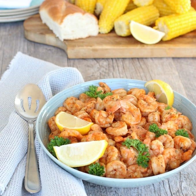 New Orleans bbq shrimp garnished with lemon wedges in a bowl.