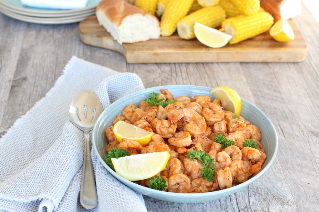 New Orleans bbq shrimp garnished with lemon wedges in a bowl.