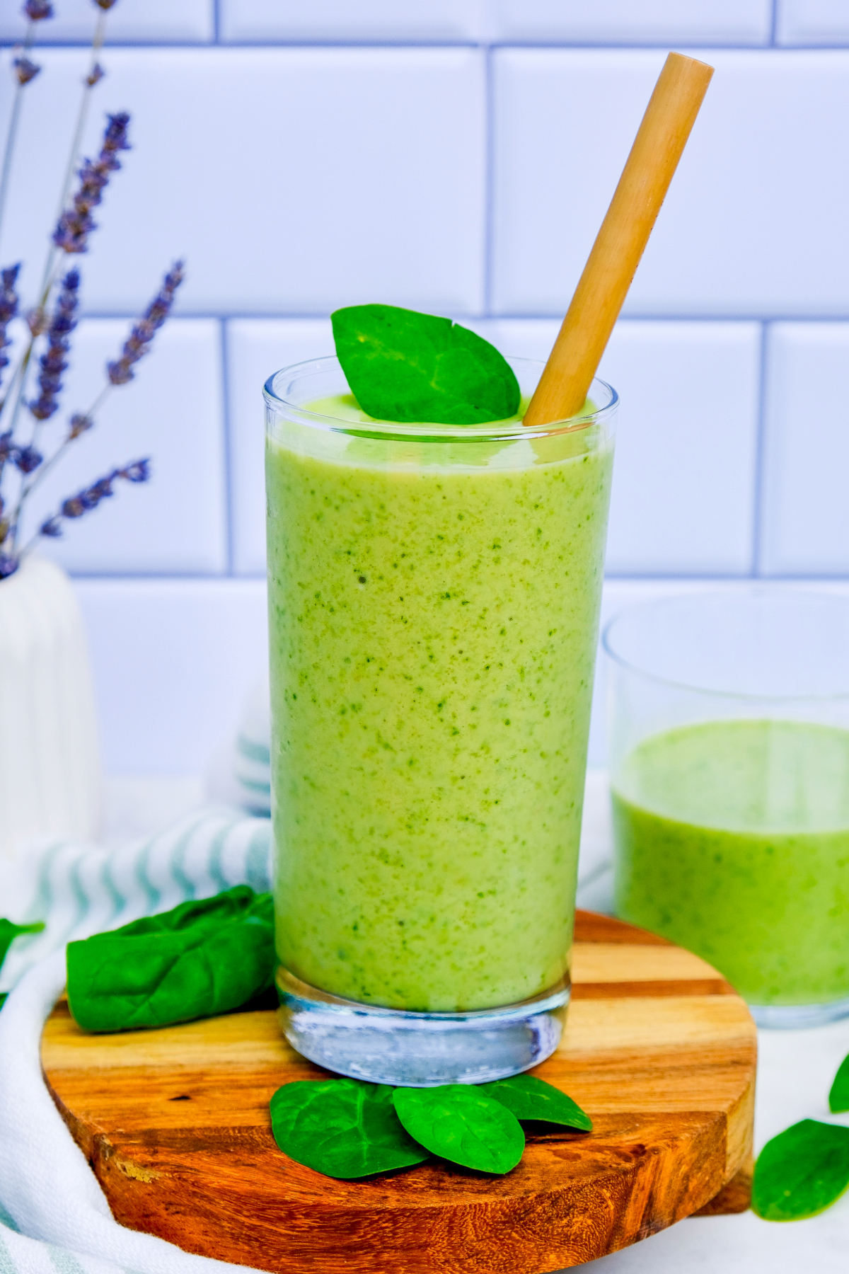 Homemade Spinach Avocado Smoothie in a clear glass with a bamboo straw.