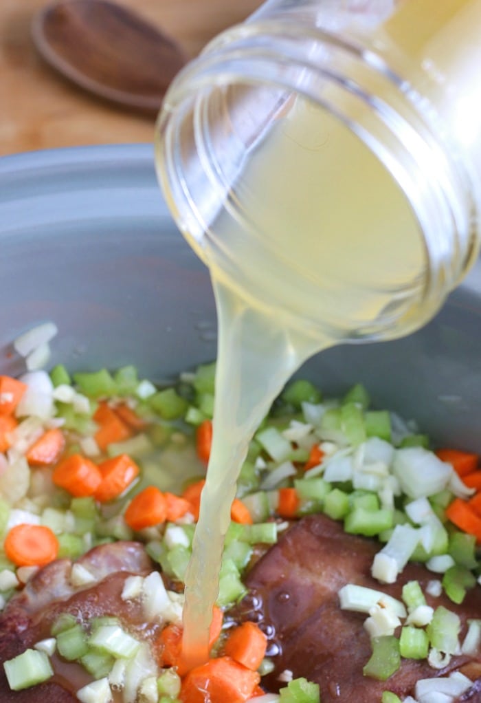 This image shows us the stock being added to the crock pot full of other ingredients so it can start to simmer and cook. 