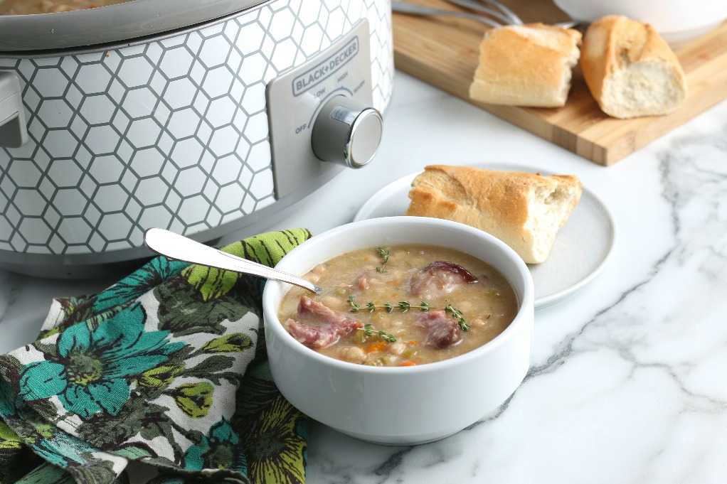 This horizontal shot shows the soup dished out into a bowl with the slow cooker in the background as well as some crusty bread! 