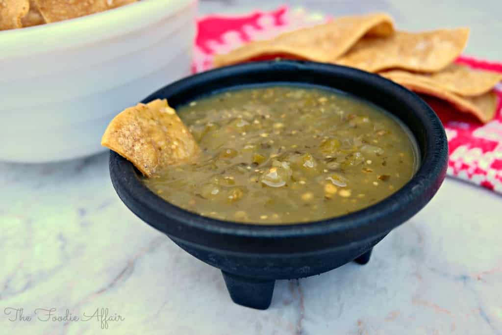 baked tortilla chips with green salsa in a black bowl