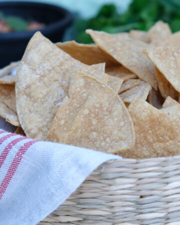 Homemade baked tortilla chips in a straw basket.