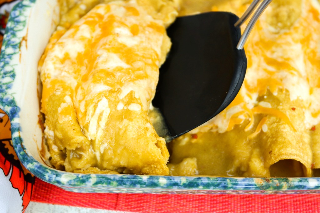 Green chili enchiladas with pre-cooked chicken in a casserole dish. 