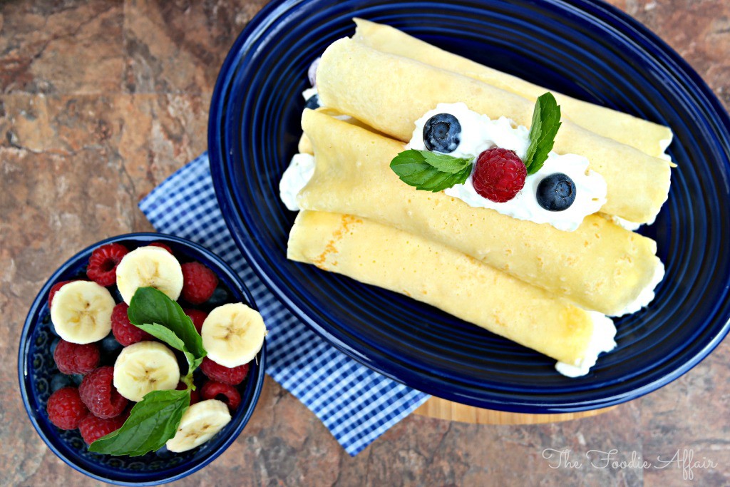 Blue plate of crepes with fresh berries and whipped cream